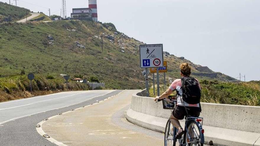 Una mujer pedalea por la senda mixta para bicis de paseo y peatones, pegada al arcén que utilizan los cicloturistas a mayor velocidad, en Cabo Silleiro. // Ricardo Grobas
