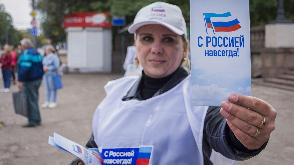 Una voluntaria reparte panfletos con el mensaje &quot;Siempre con Rusia&quot; durante la campaña para el referéndum para unirse a la Federación Rusa, en Luhansk, Ucrania