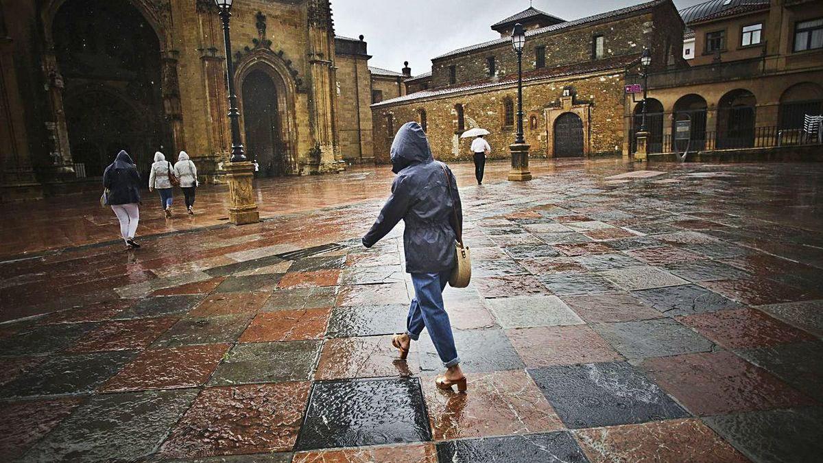 Turistas en la plaza de la Catedral bajo la persistente lluvia.