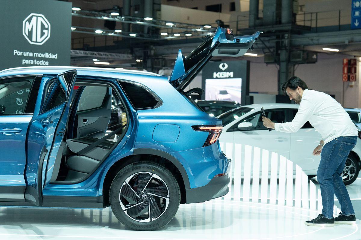 Un hombre realiza una fotografía a un vehículo de la marca asiática MG en una muestra, en imagen de archivo.