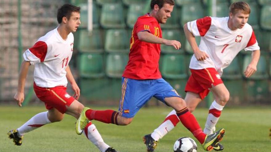 El jugador español Juan Mata (c) controla el balón entre los polacos Ariel Borysiuk (i) y Tomasz Kupisz durante el partido Polonia-España, de clasificación para el Mundial de fútbol sub-21, disputado en Grodzisk Wielkopolski, Polonia, hoy, martes 7 de septiembre de 2010. España ganó el encuentro por 0-1.