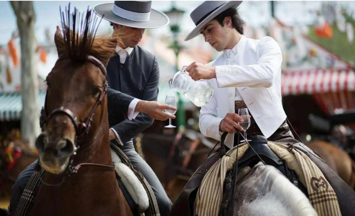 Los jinetes se sirven rebujito en la Feria de Sevilla