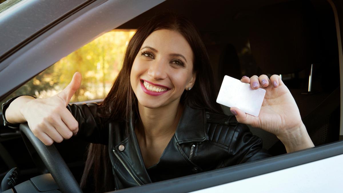 Una chica muestra el carnet de conducir que acaba de conseguir.