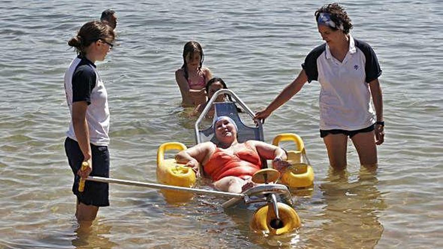 Una mujer, en una silla anfibia de la Fundación María José Jove en la playa de Oza.