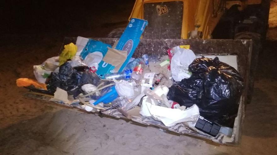 Basura, incluidas bolsas de residuos domésticos, retirada con una pala en una playa dianense