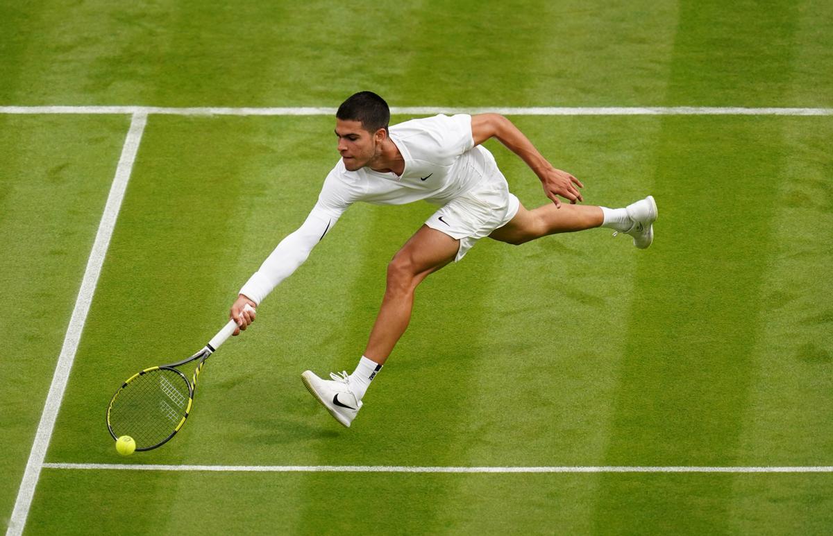 Archivo - El tenista español Carlos Alcaraz intenta devolver una pelota en Wimbledon 2022