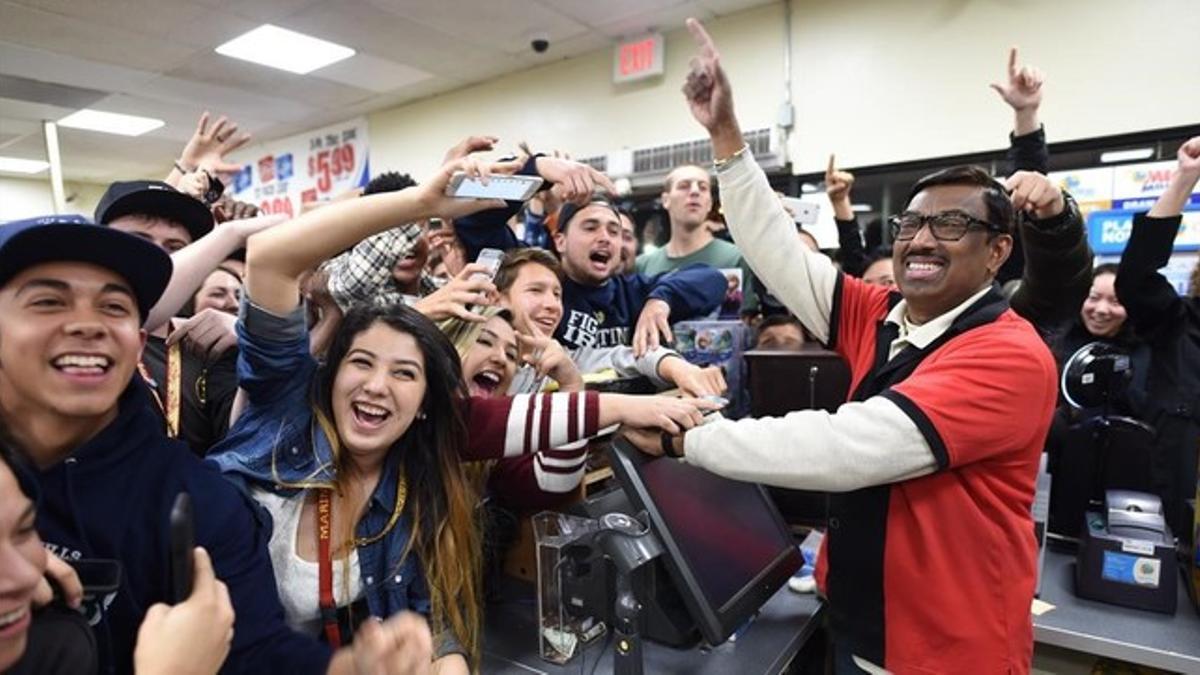 Varios clientes celebran el resultado de la Powerball con el dueño de un establecimiento que vende boletos de lotería, en Chino Falls (California).