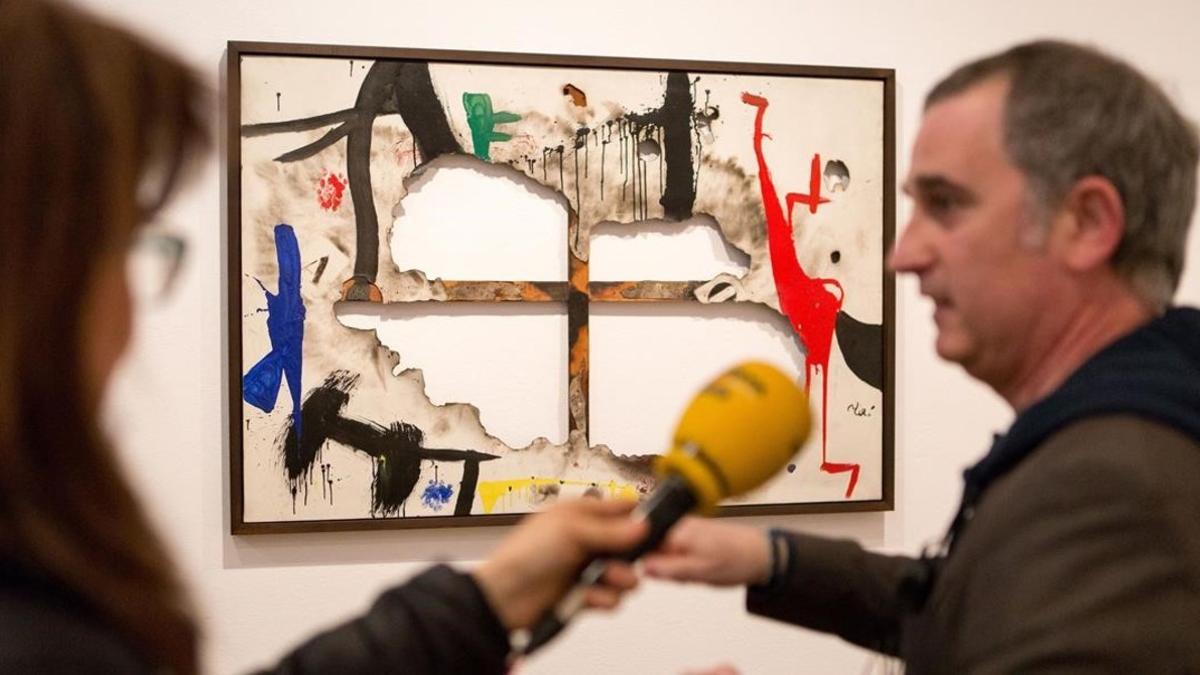 'Tela quemada 1', de Joan Miró, en la exposición 'Autogestión', en la Fundació Miró, con el comisario de la misma, el artista Antonio Ortega.