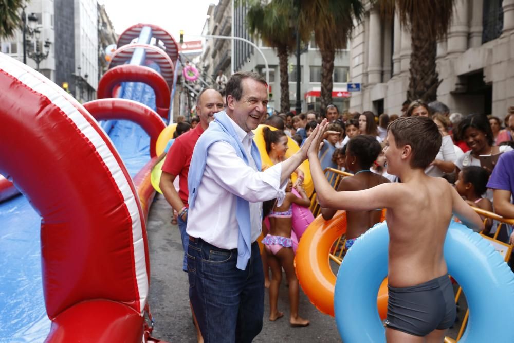 Cientos de personas disfrutan del tobogán acuático en la calle Colón