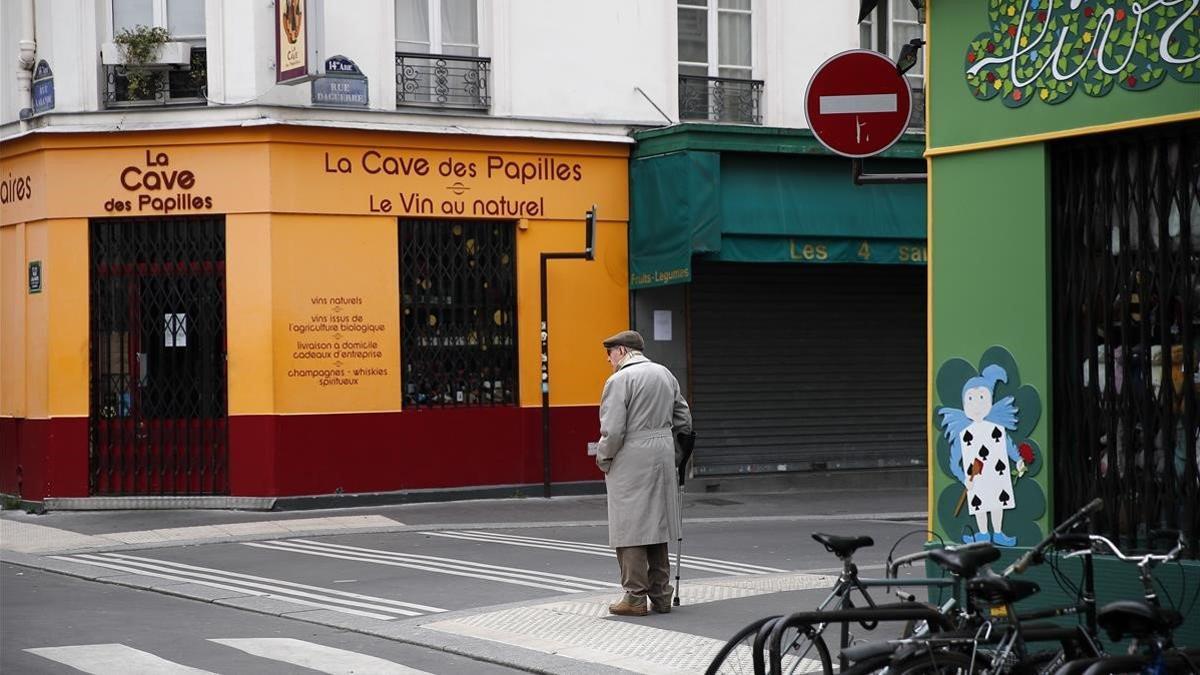 Un hombre camina por una calle desierta y con comercios cerrados en París, este martes.