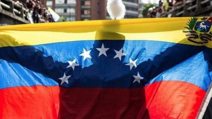 Un hombre sostiene la bandera de Venezuela