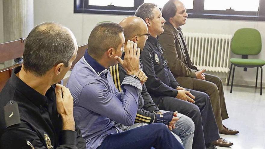 Los tres procesados, custodiados por policías en el banquillo de la Audiencia de Vigo.