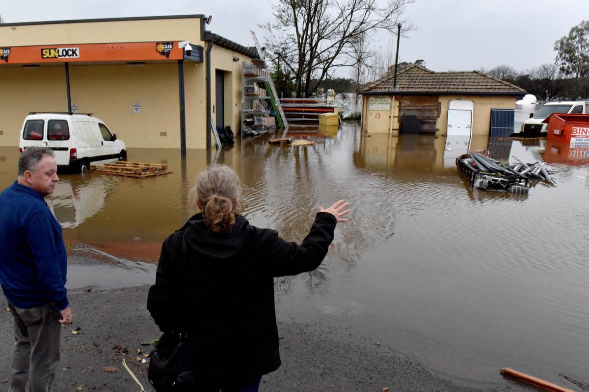 La gente mira las calles inundadas debido a las lluvias torrenciales en el suburbio de Camden en Sydney el 3 de julio de 2022. - Miles de australianos recibieron la orden de evacuar sus hogares en Sydney el 3 de julio cuando las lluvias torrenciales azotaron la ciudad más grande del país y las inundaciones inundaron sus afueras. (Foto de Muhammad FAROOQ / AFP)