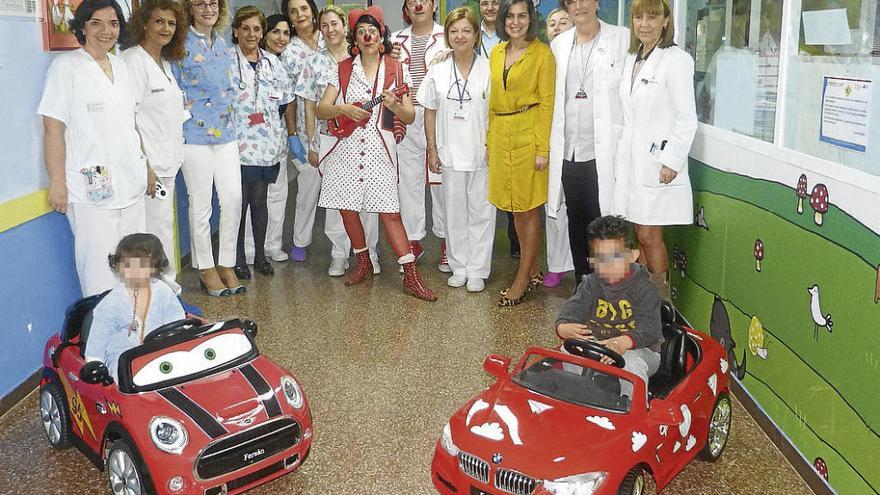 Personal del Hospital y representantes de Fersan tras algunos de los coches donados.