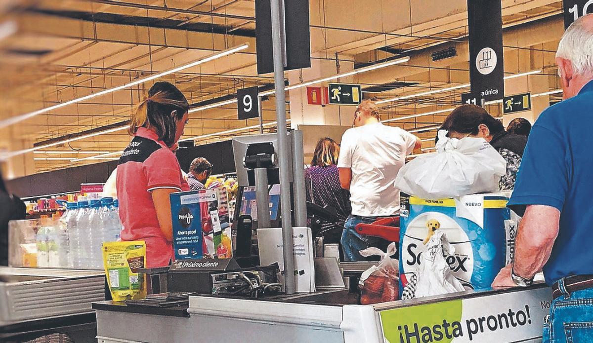 Clientes pasan por la caja de un supermercado.
