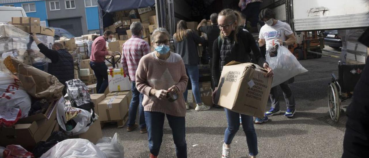 Voluntarios cargan ayuda humanitaria en un tráiler en Colloto. | Miki López