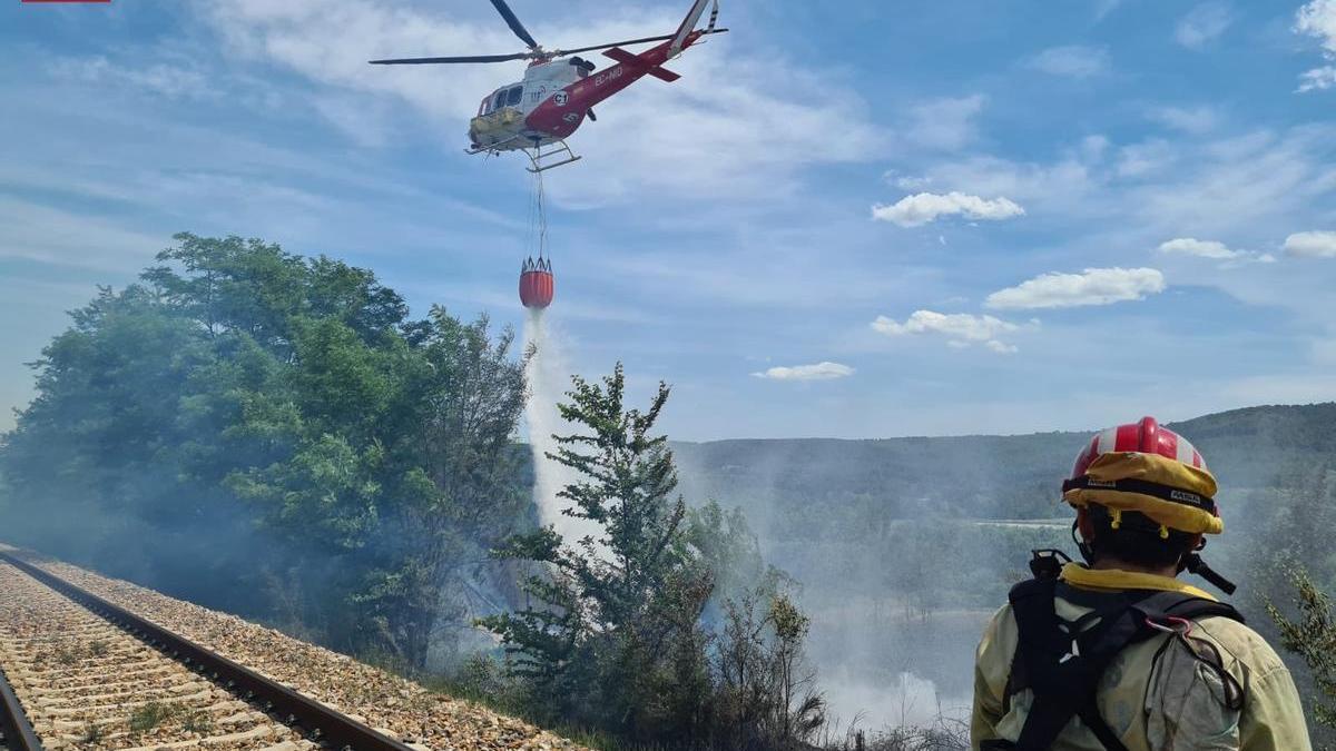 Los bomberos trabajan en la extinción de uno de los incendios de Segorbe junto a las vías.