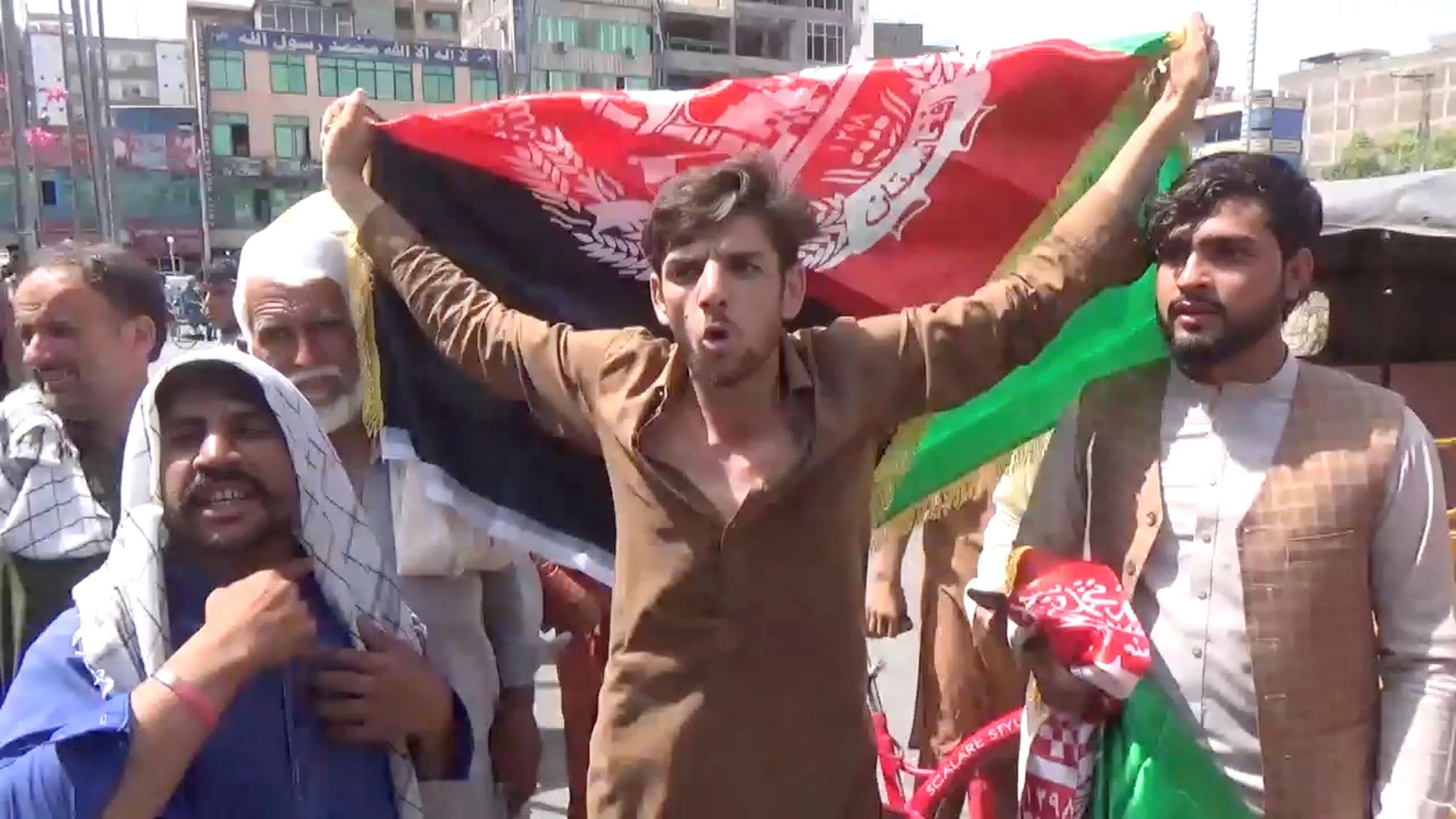 Civiles afganos protestan contra los talibanes con una bandera de Afganistán.