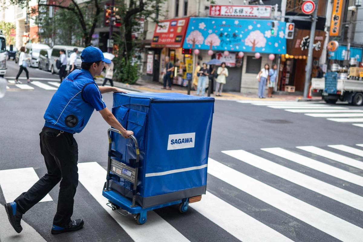Un repartidor de la empresa Sagawa, con una chaqueta con ventilador para refrescarse durante la jornada laboral, en una calle de Tokio.