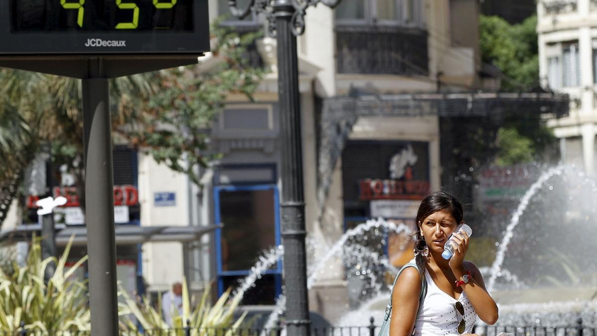 Una joven se refresca con una botella de agua ante el sofocante calor en València