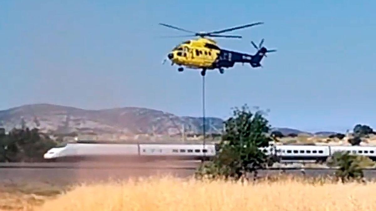 Un tren AVE pasa junto a un helicóptero de Extinción de Incendios de Castilla la Mancha.