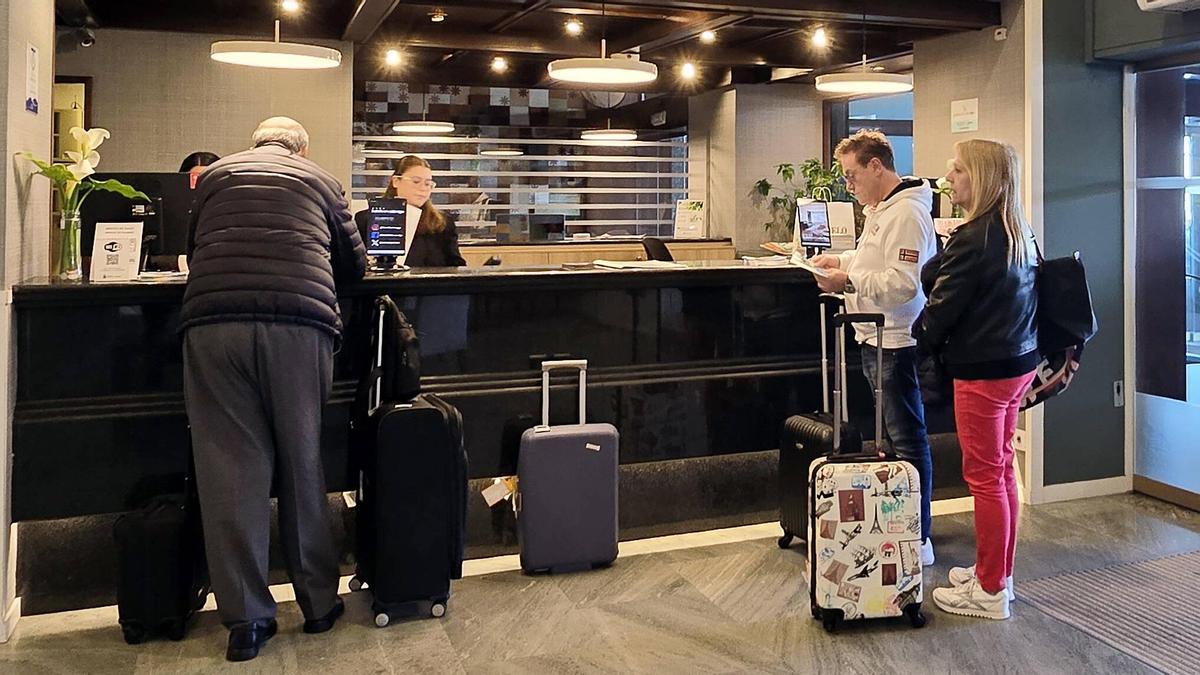 Turistas con maletas en la recepción de un hotel en Vigo.