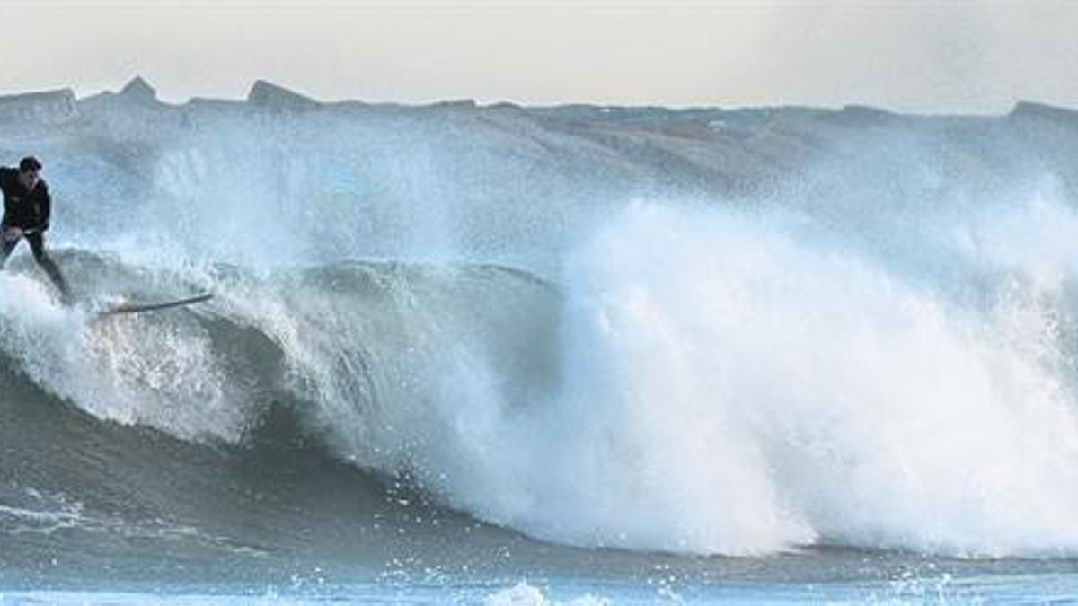 Un aficionado al surf aprovecha las olas cerca del Hotel Vela de Barcelona.