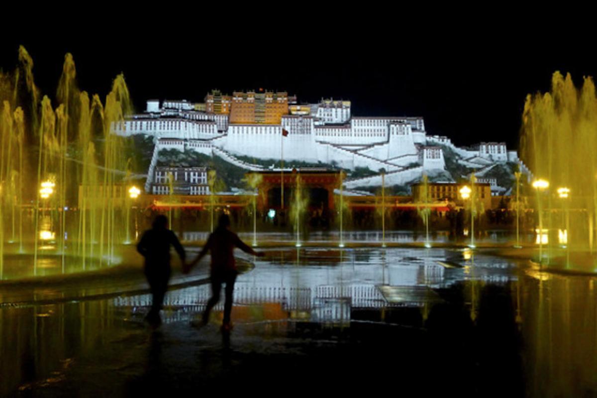 Uns turistes caminen entre les fonts davant el palau Potala a Lhasa(Tibet)