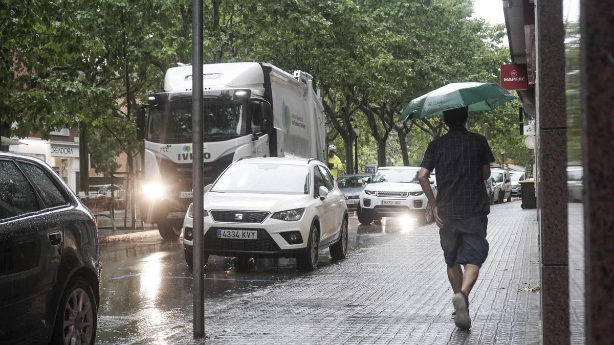 Un home camina pel carrer amb un paraigua, en una imatge d'arxiu
