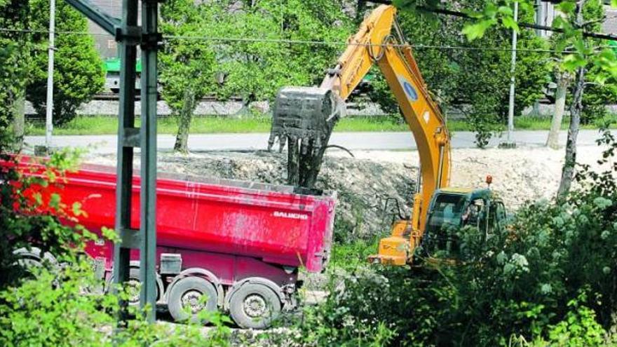 Una excavadora carga lodo del fondo de la ría en un camión.