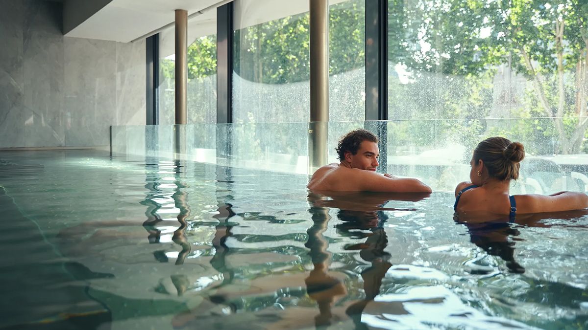 La piscina climatizada, con luz natural y vistas a la Plaza de España, invita a relajarse en pareja o en solitario