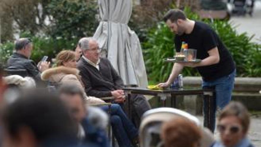 Un camarero atendiendo a clientes en una terraza.