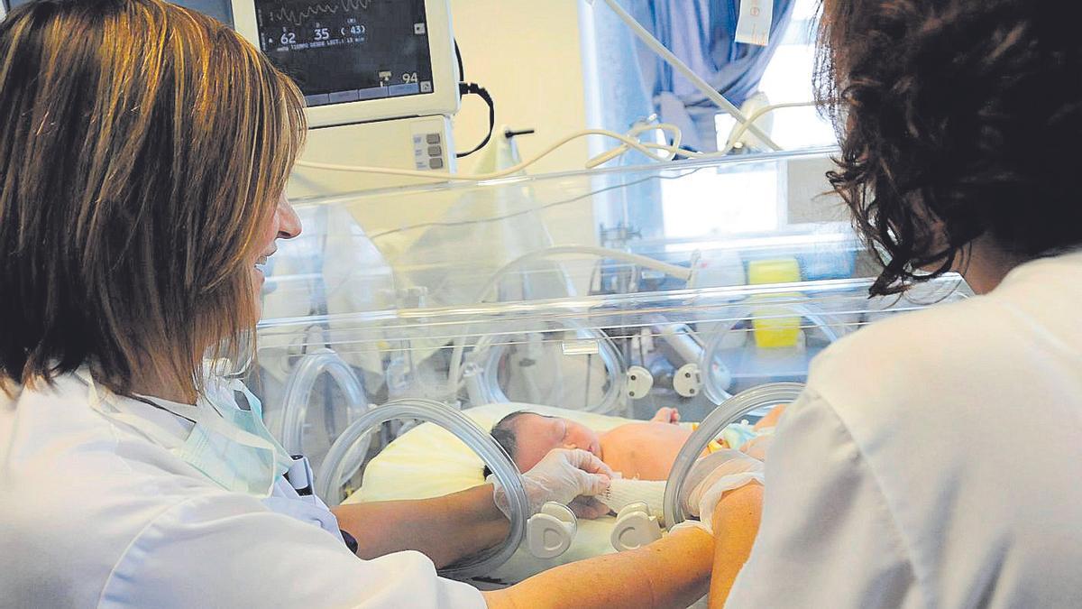 Dues sanitàries atenen un nen dins una incubadora, al servei de Neonatologia d’Althaia