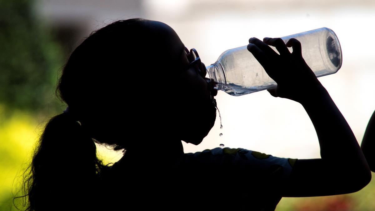 Una niña bebe agua para sofocar las altas temperaturas.