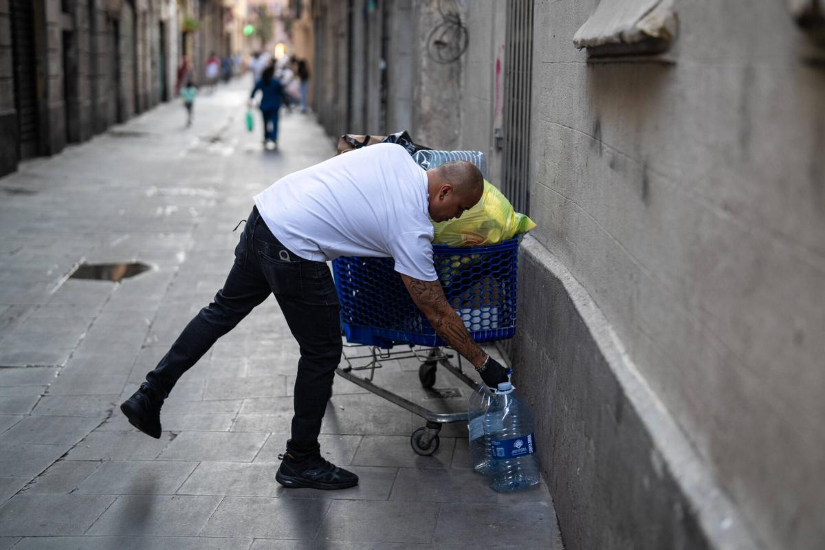 Barcelona. Jeffrey, propietario del bar Never, en la calle Cera 17 del barrio del Raval, retira con un carro de la compra las bolsas de basura acumuladas frente a su establecimiento antes de abrir el local, una situación que denuncia como habitual cada tarde. 29 de julio de 2026. Sociedad. AUTOR: ZOWY VOETEN