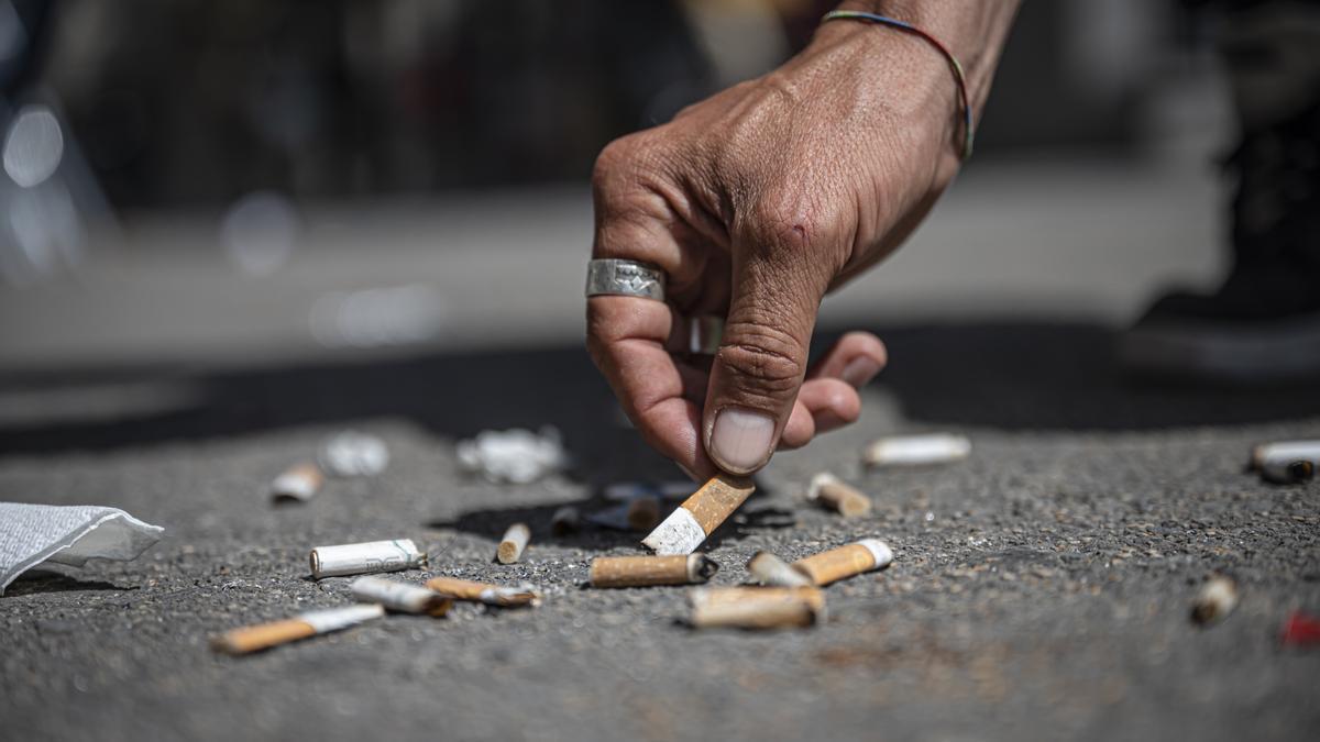 Una persona recoge una colilla de cigarrillo tirada en el suelo de Barcelona.