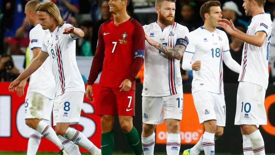 Cristiano Ronaldo, entre jugadores islandeses al finalizar el partido.