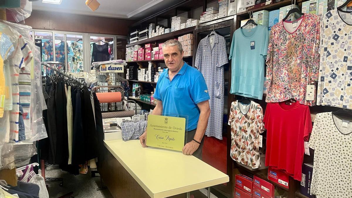 Pepito García, con la placa del Ayuntamiento, que acredita a su tienda como uno de los negocios históricos del concejo de Oviedo.