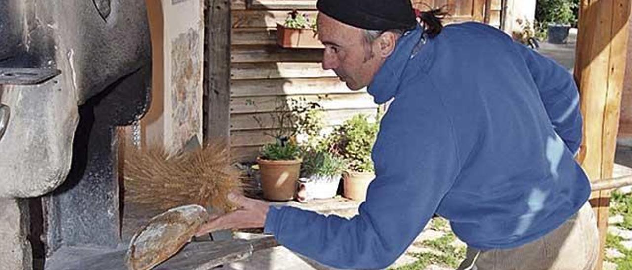 Bartomeu Morro saca pan del horno de leÃ±a con ayuda de una larga pala de madera.