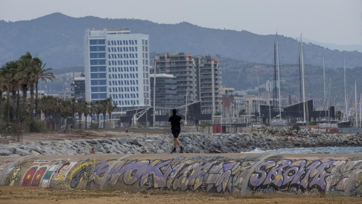 Un hombre practica deporte sobre el lomo del colector interceptor de levante, con Badalona al fondo, una instalación caducada y fuera ya de tiempo.