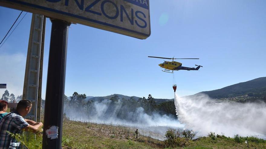 Un helicóptero descarga agua en el incendio de Cerponzóns.