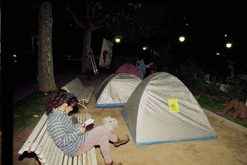 Una participant a l’acampada llegeix en un banc de la plaça