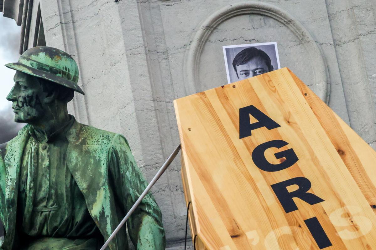 Agricultores cuelgan un ataúd que simboliza el fin de la agricultura bajo un retrato del primer ministro belga, Bart De Wever.
