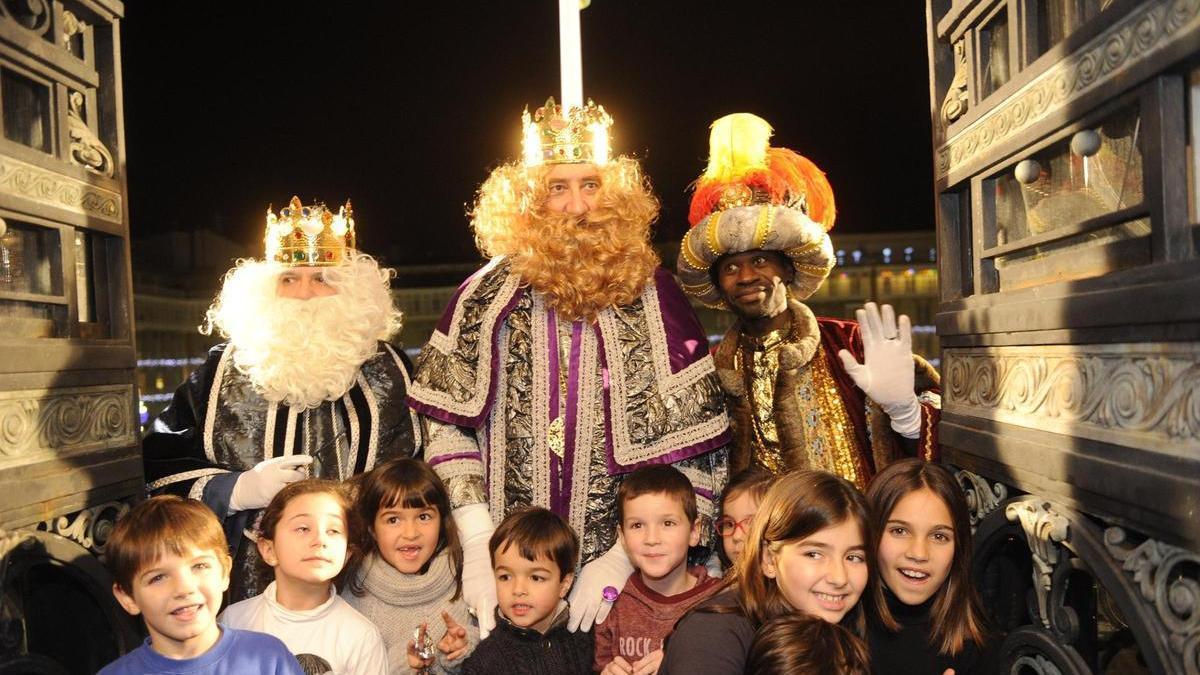 Los Reyes Magos posan con niños en el balcón del Palacio Municipal tras el desfile de la Cabalgata.