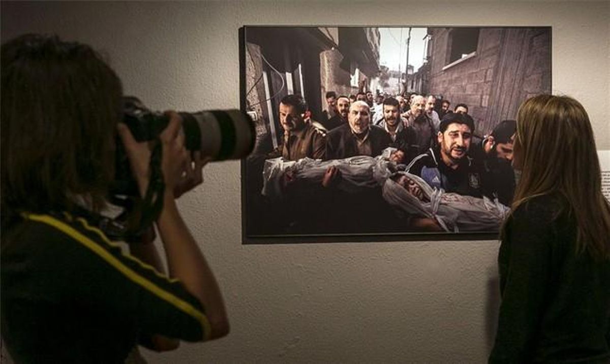 Un fotògraf i un visitant contemplen la foto guanyadora del World Press Photo 2013, al CCCB.