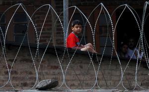 Un nen observa a través del filat que protegeix la tomba d’un màrtir musulmà Srinagar, regió de Caixmir, Índia.