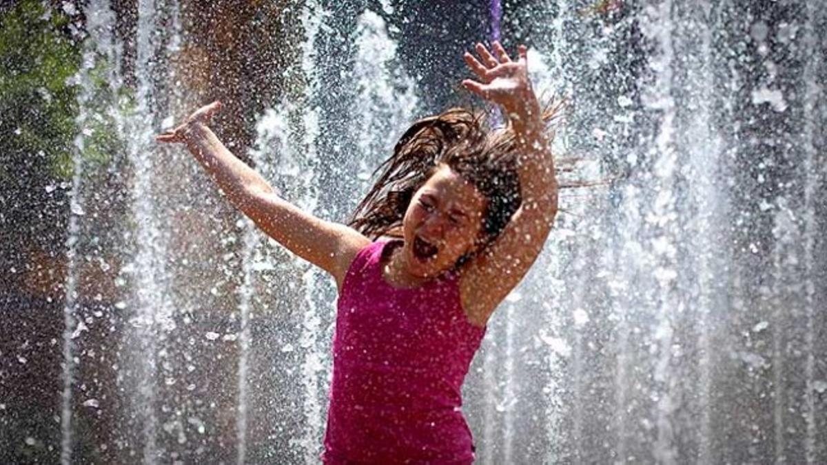 Una nena es diverteix en una font d’aigua als afores d’un centre comercial a Xina.