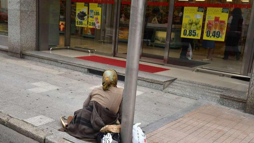 Una mujer pide limosna en el suelo frente a un supermercado en Pontevedra. // Gustavo Santos