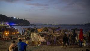 Personas migrantes instalados en barracas en una playa de Ceuta.