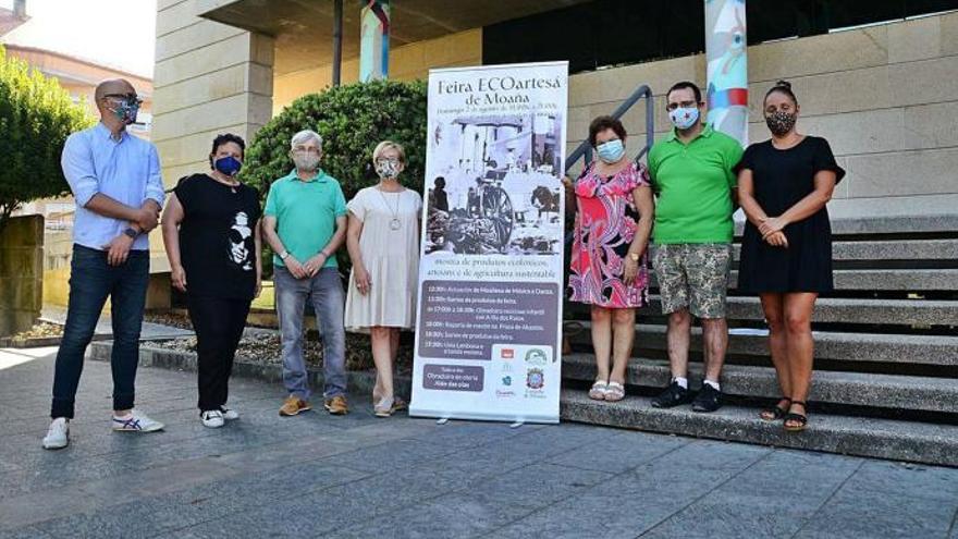 Los organizadores del evento junto al cartel que anuncia la Feira Ecoartesá de Moaña.